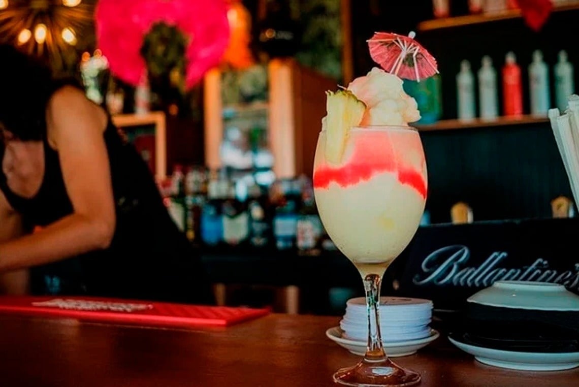 un cóctel en una copa sobre una mesa junto a un cartel de ballantine 's