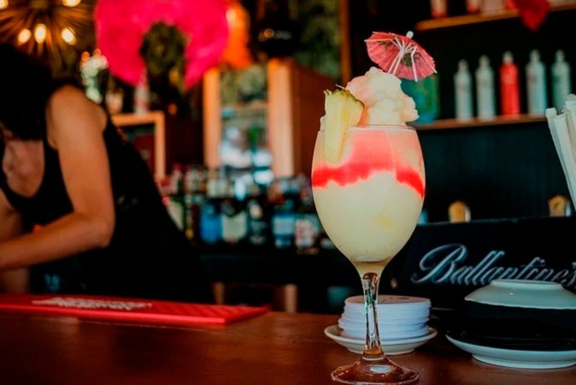 un cóctel en una copa sobre una mesa junto a un cartel de ballantine 's