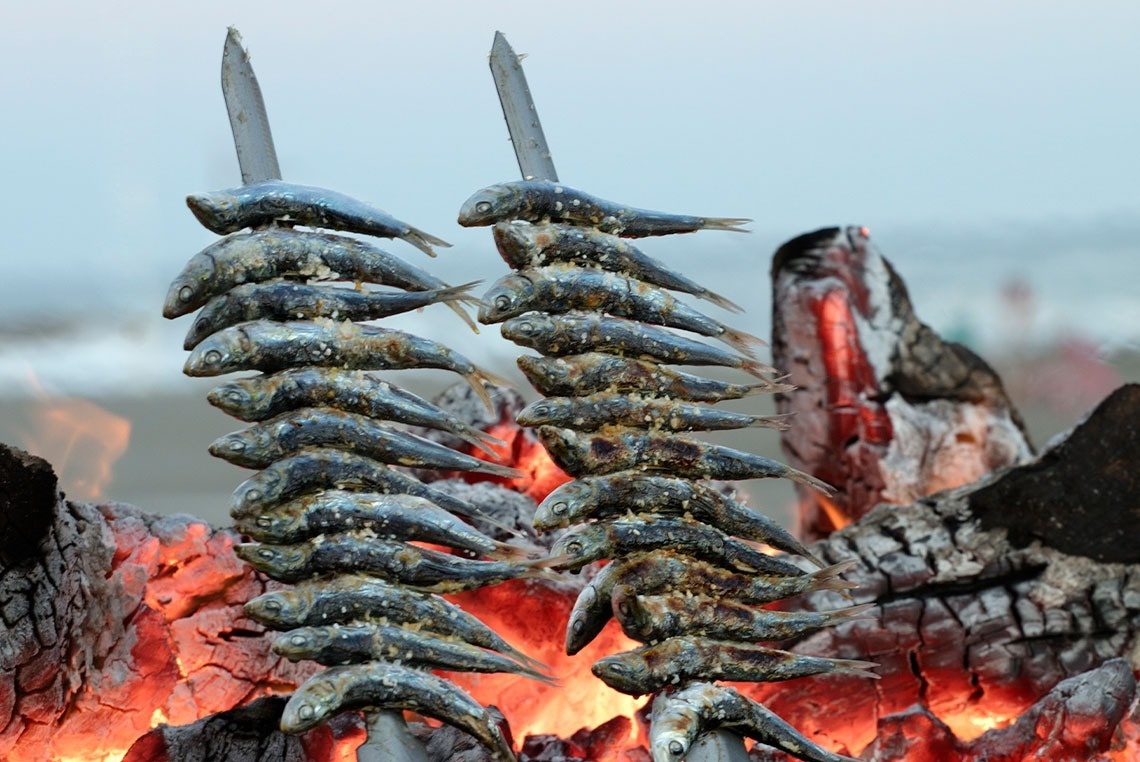 des sardines sont grillées sur un feu de bois