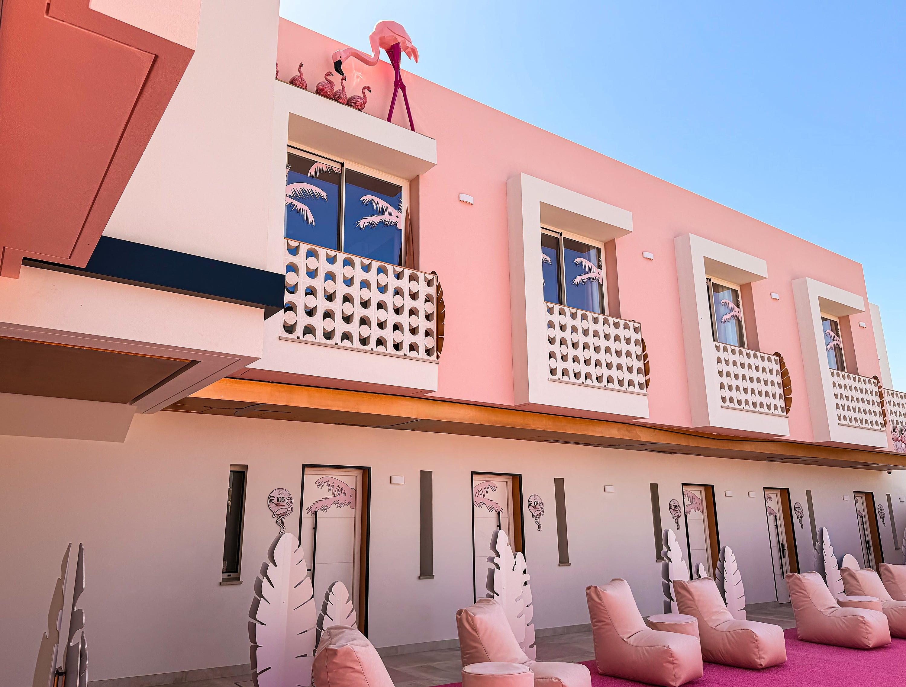 Fachada rosa vibrante de hotel com flamingos e sacadas estilosas, perfeitas paraON Pink Motel | Matalascañas.