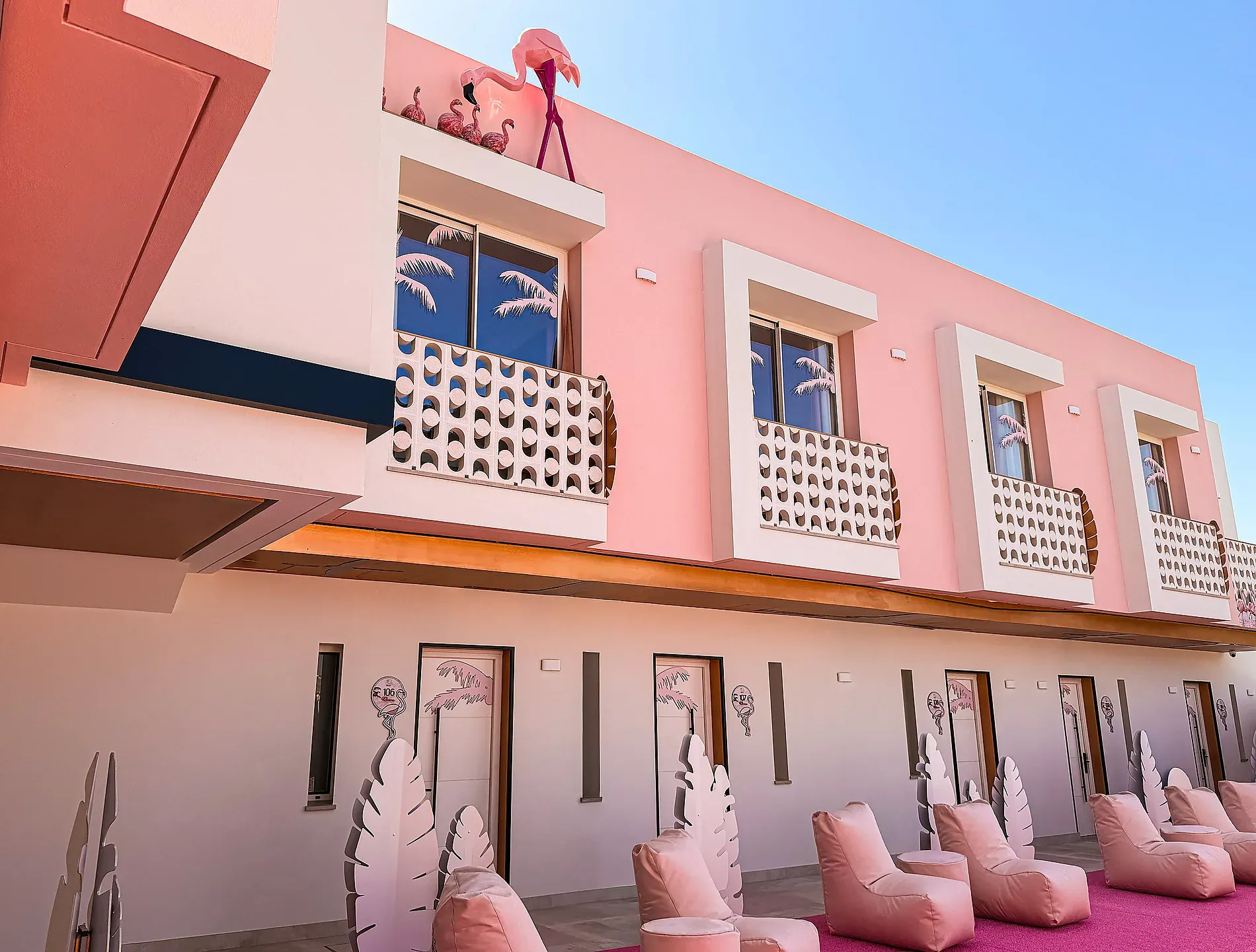 Außenansicht des pinken Hotels mit Flamingodekoration und Sitzbereich im Freien ON Pink Motel | Matalascañas