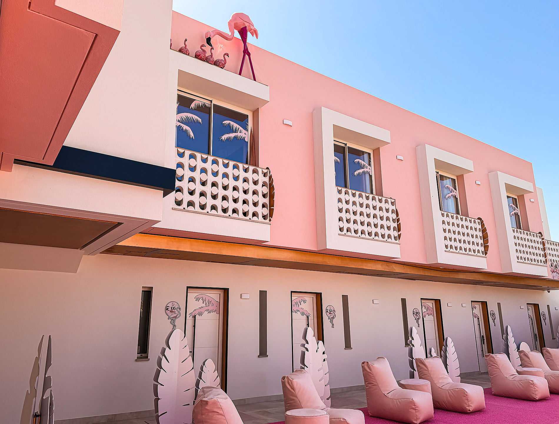 Fachada rosa vibrante de hotel com flamingos e sacadas estilosas, perfeitas paraON Pink Motel | Matalascañas.