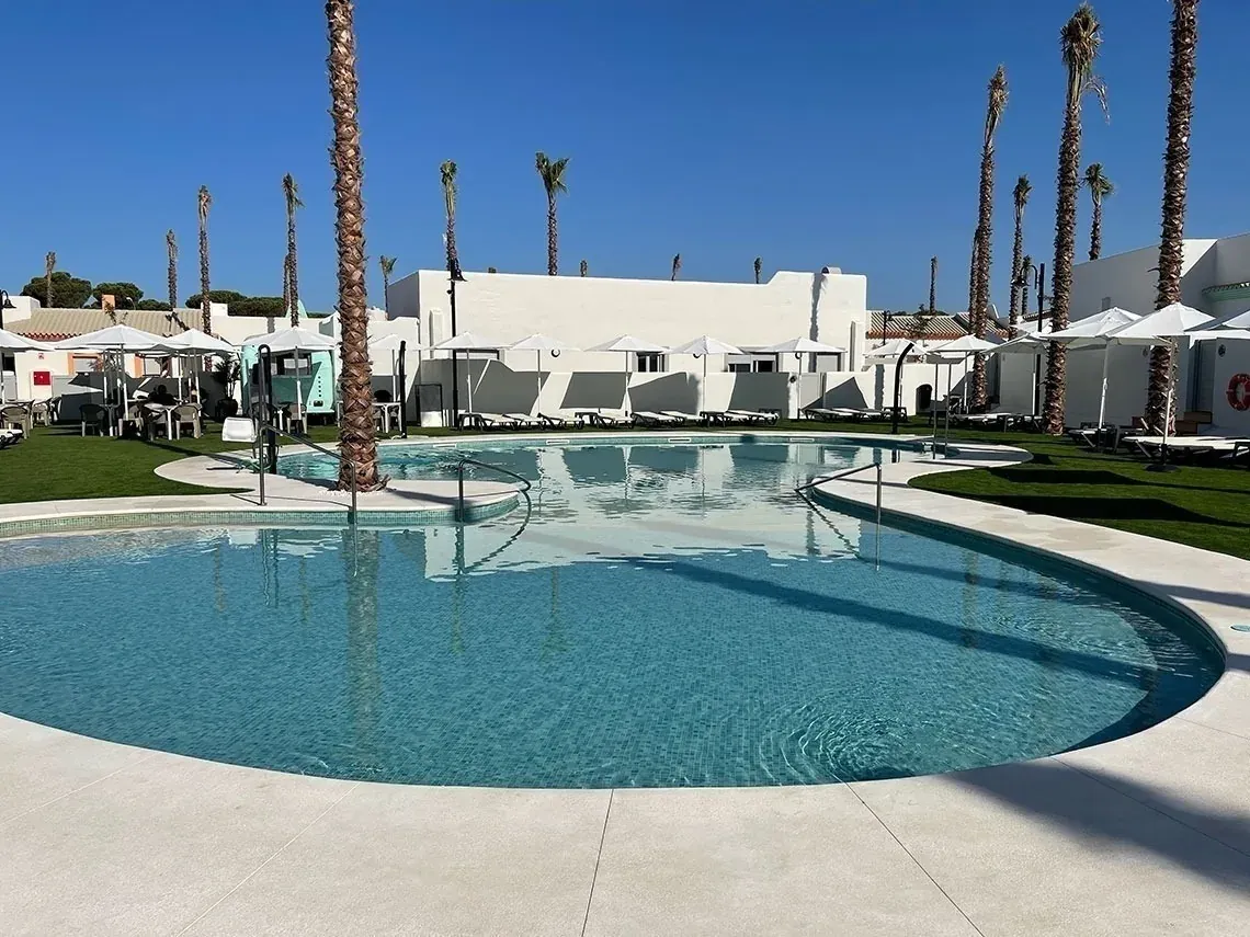 Modern pool with palm trees, grass, and loungers. Perfect for ON Corporativa.