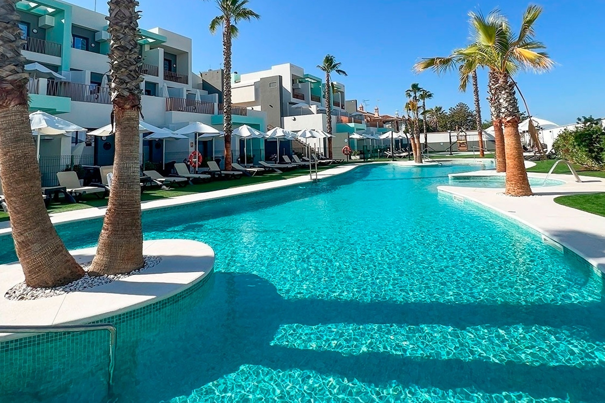 a large swimming pool surrounded by palm trees and chairs