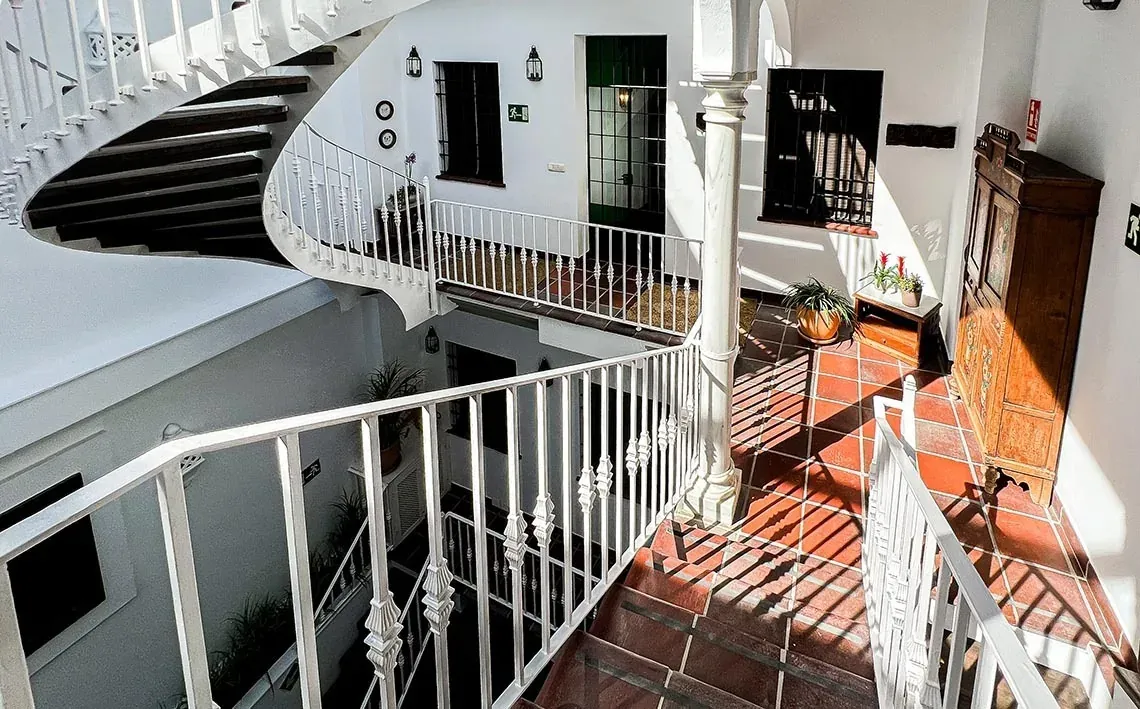 Escadas brancas curvas e pátio ensolarado no EM Acebuchal 23 El Rocio | Almonte, Huelva | On Hotels.