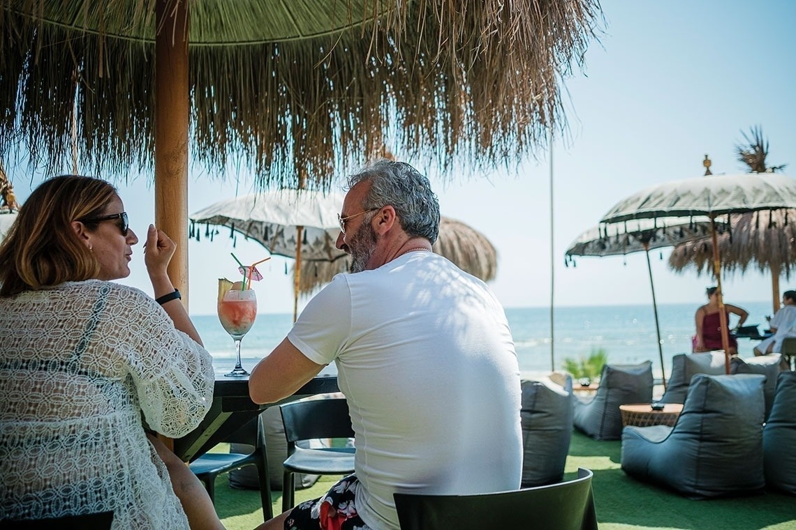 un hombre y una mujer están sentados en una mesa con una bebida en la mano
