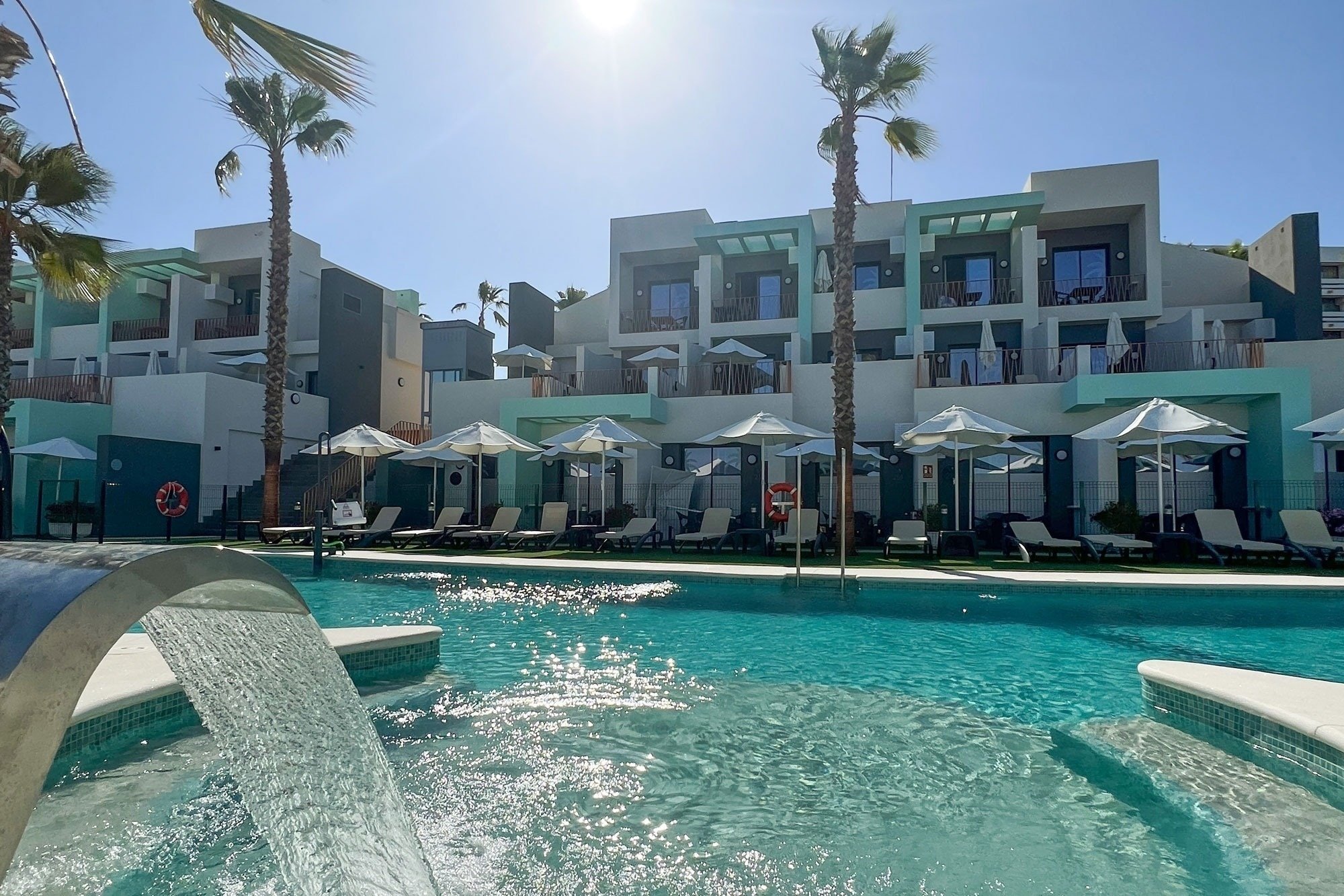 una piscina rodeada de sillas y sombrillas en un resort