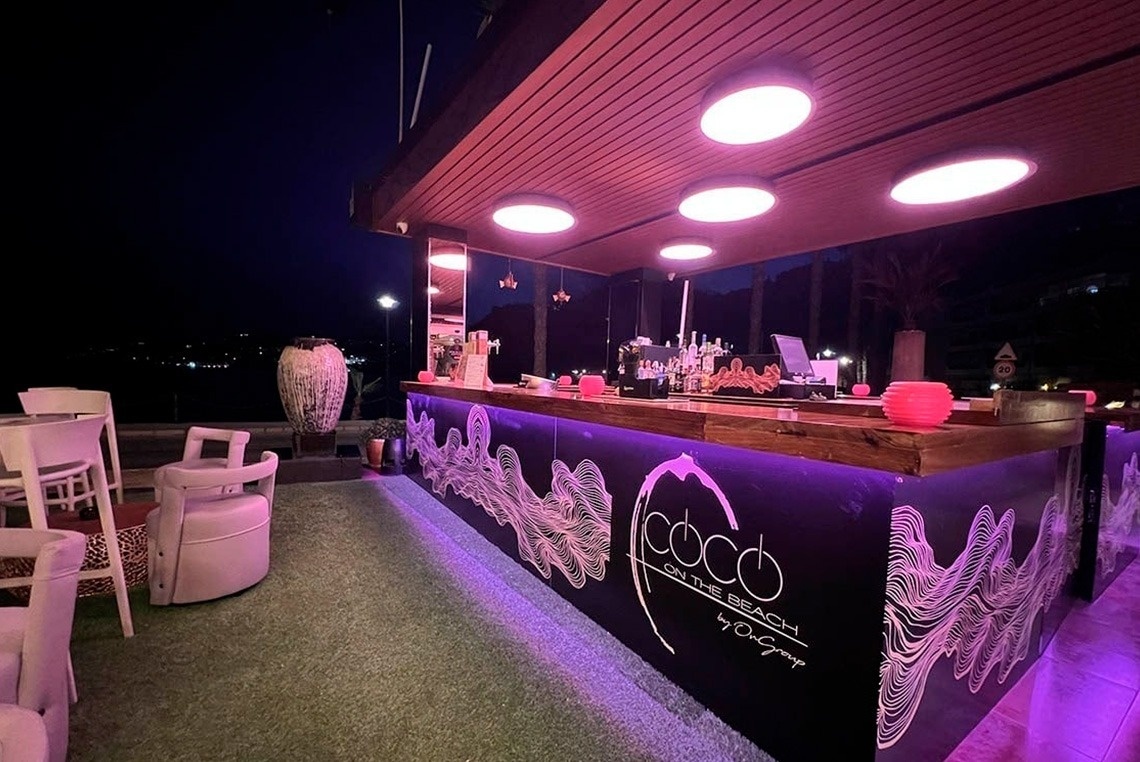 a bar called coco on the beach is lit up at night