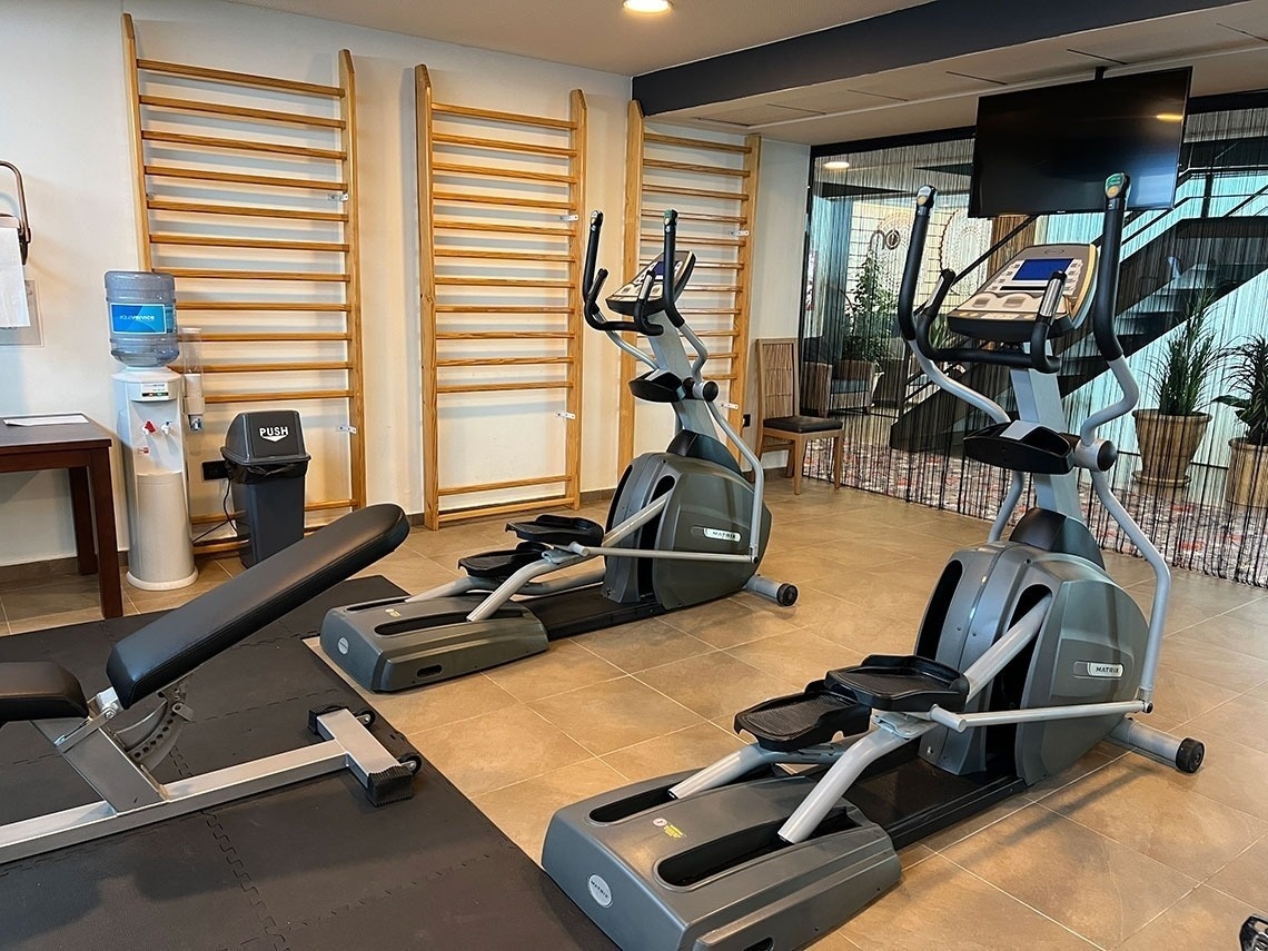 a gym with two ellipticals and a bench