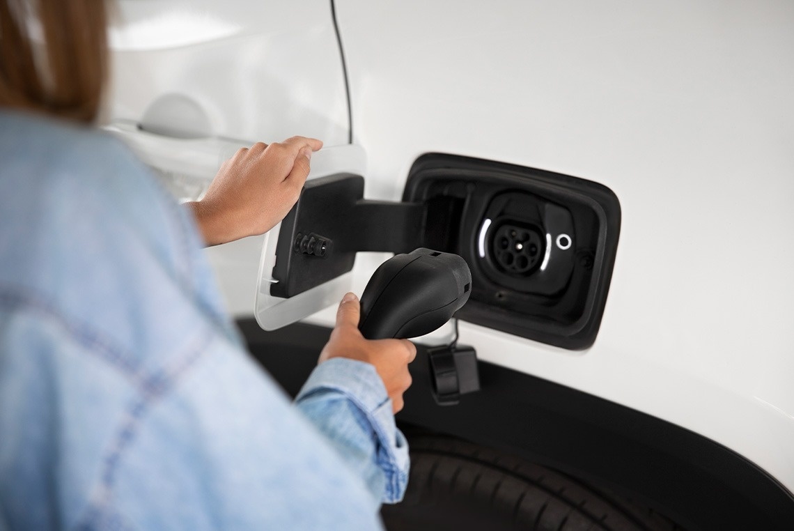a woman is plugging a charger into an electric car