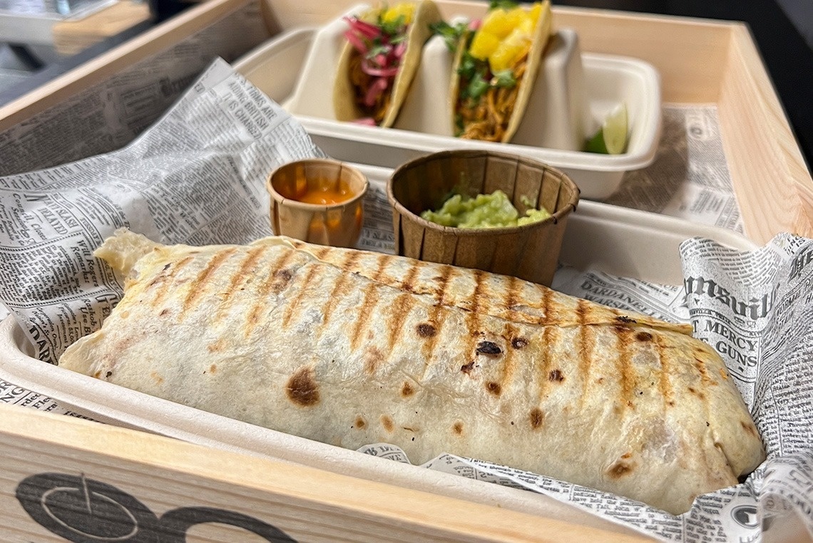 un burrito se sienta en una caja de madera junto a dos tacos