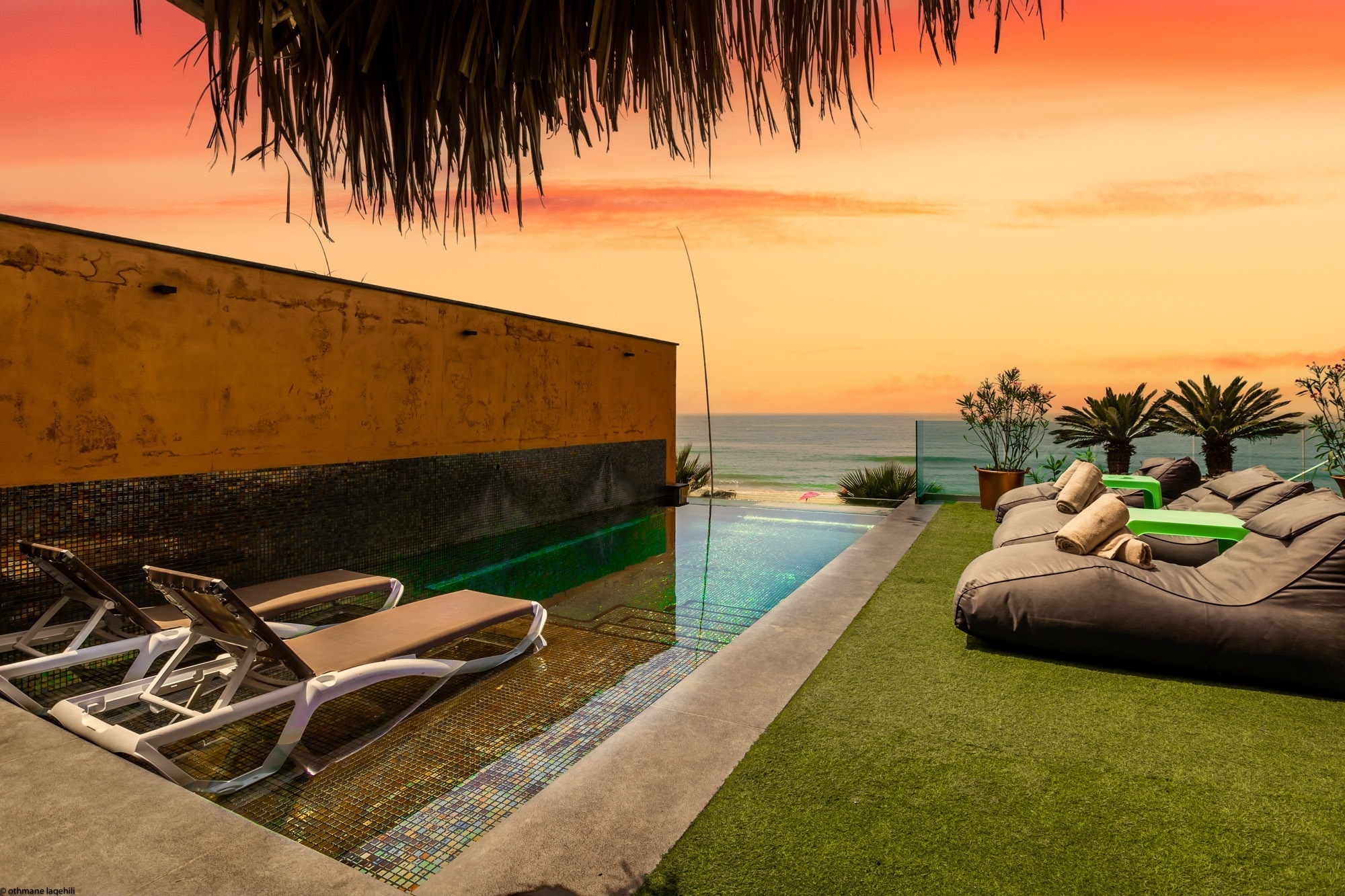 a swimming pool with a view of the ocean at sunset