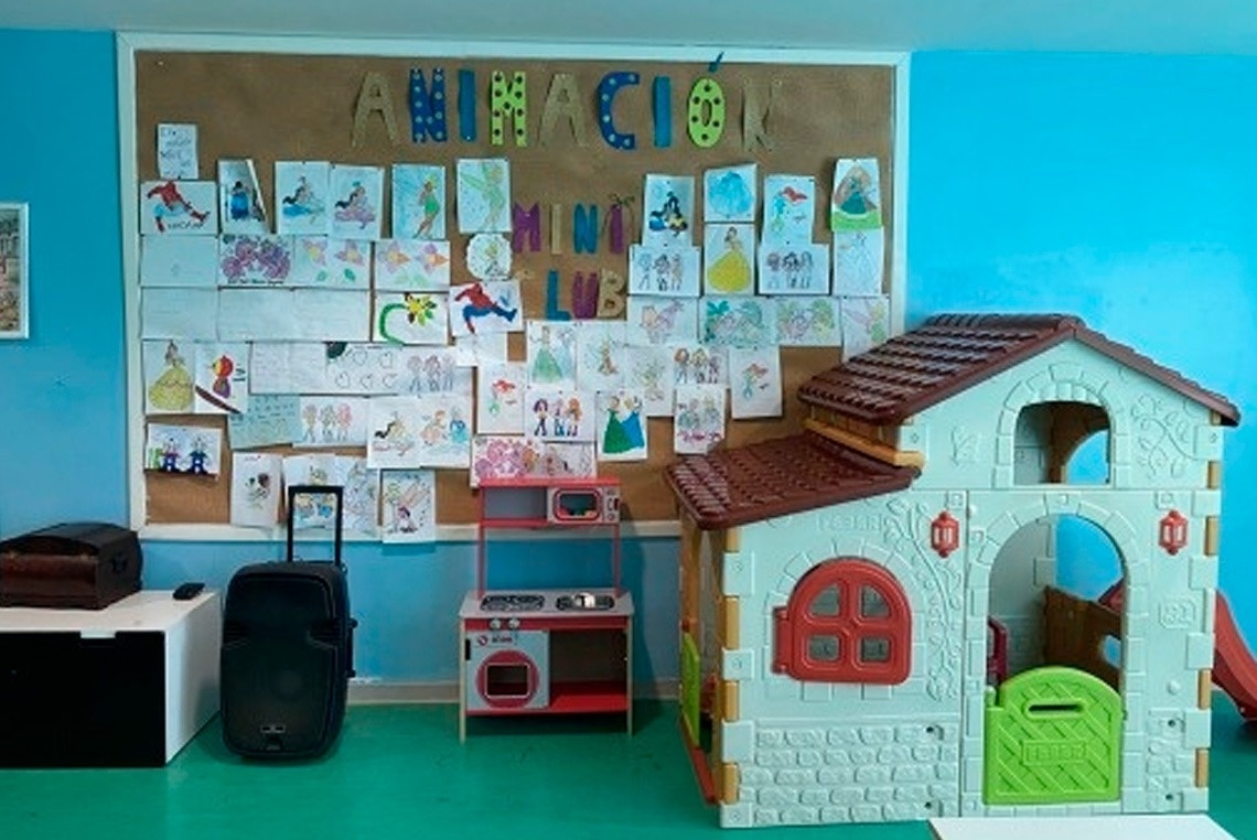 uma sala de brinquedos com uma casa de brinquedo e um painel de desenhos