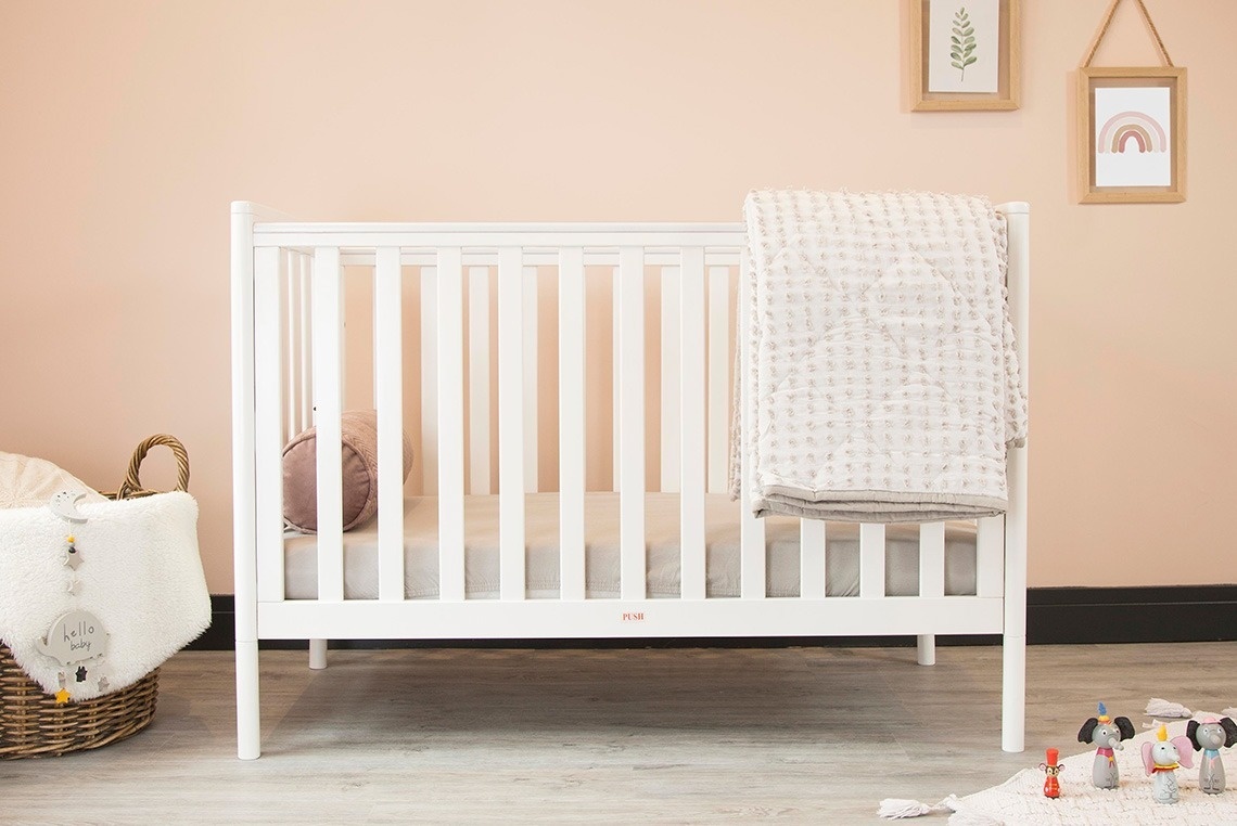 a white baby crib with a blanket on it