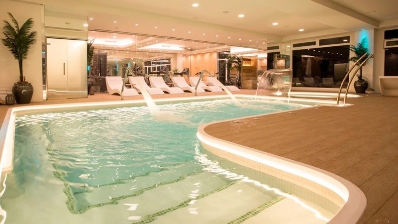 a large indoor swimming pool with chairs and a waterfall