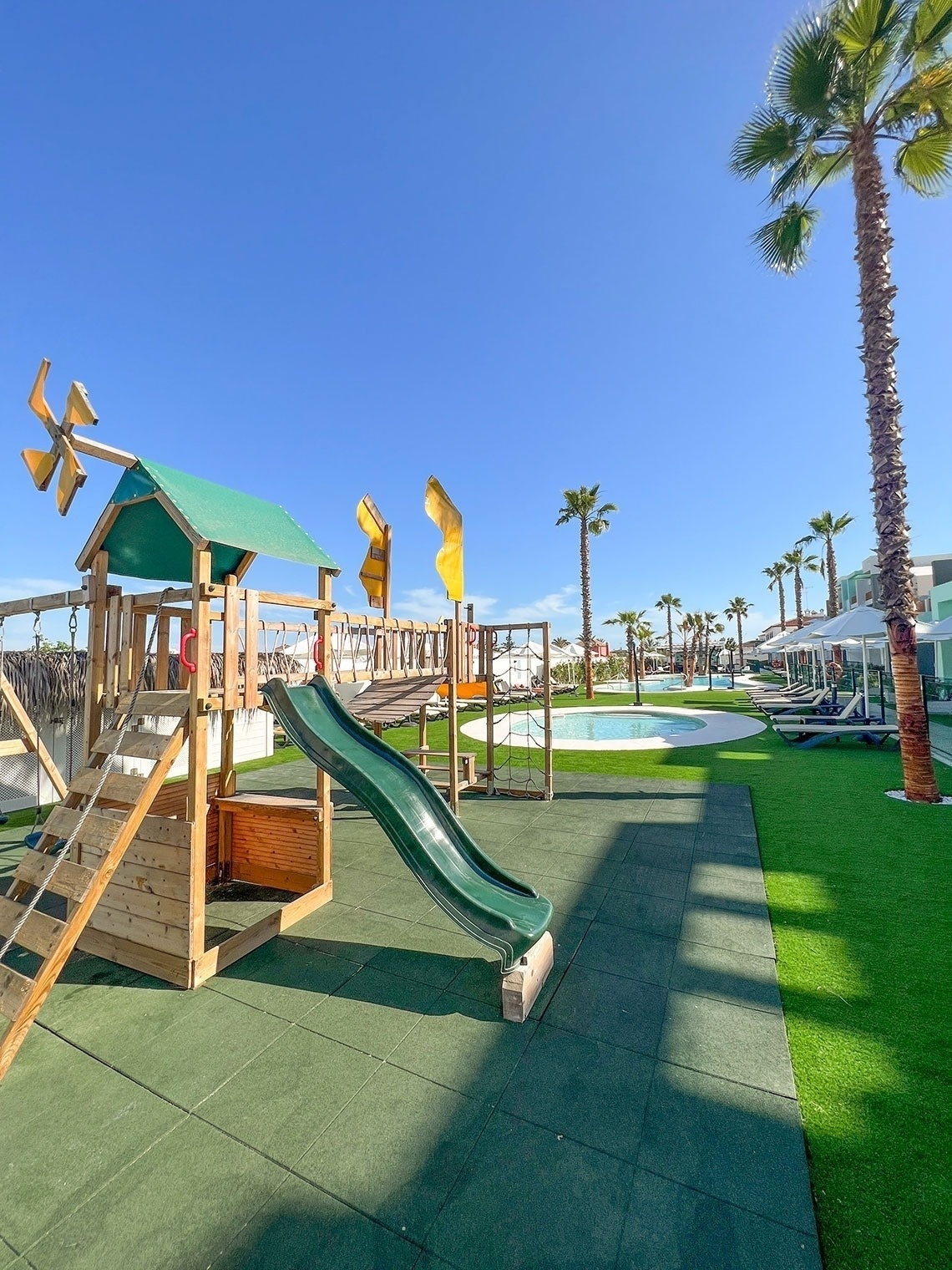 a playground with a green slide and a windmill