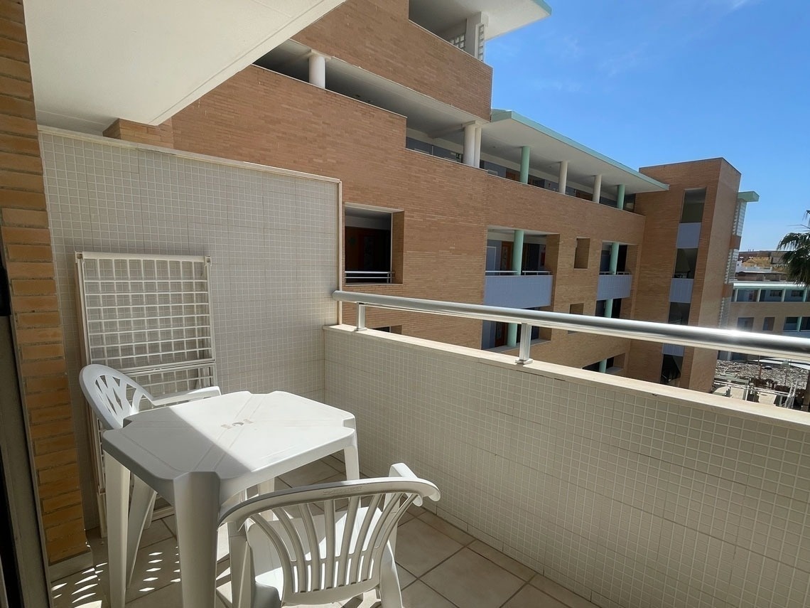 a balcony with a table and chairs and a brick building in the background