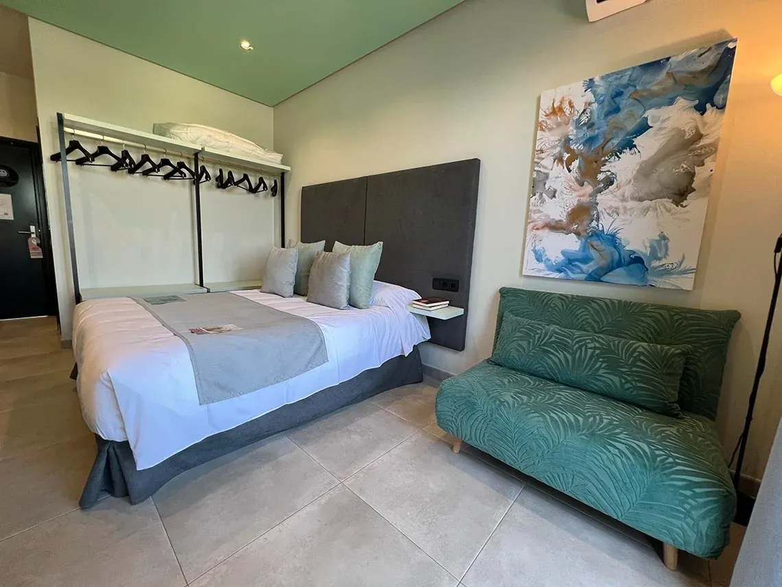 Chambre double confortable avec lit, coussins et tableau abstrait à Matalascañas. Réservation sur Groupe Hôtels ON.