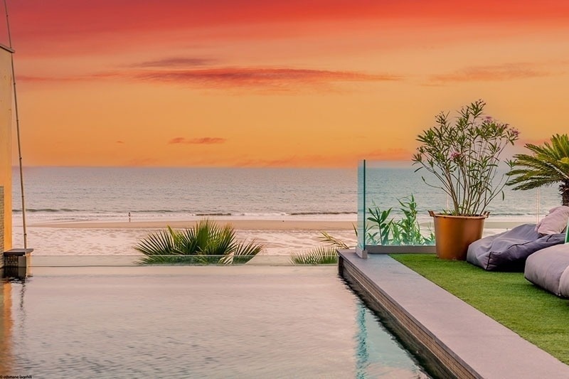 a swimming pool with a view of the ocean at sunset