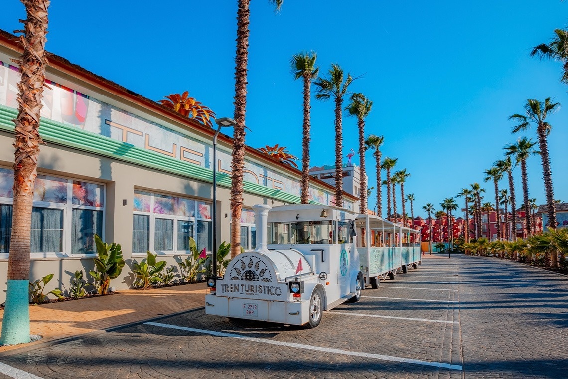 un tren turístico está estacionado frente a un edificio
