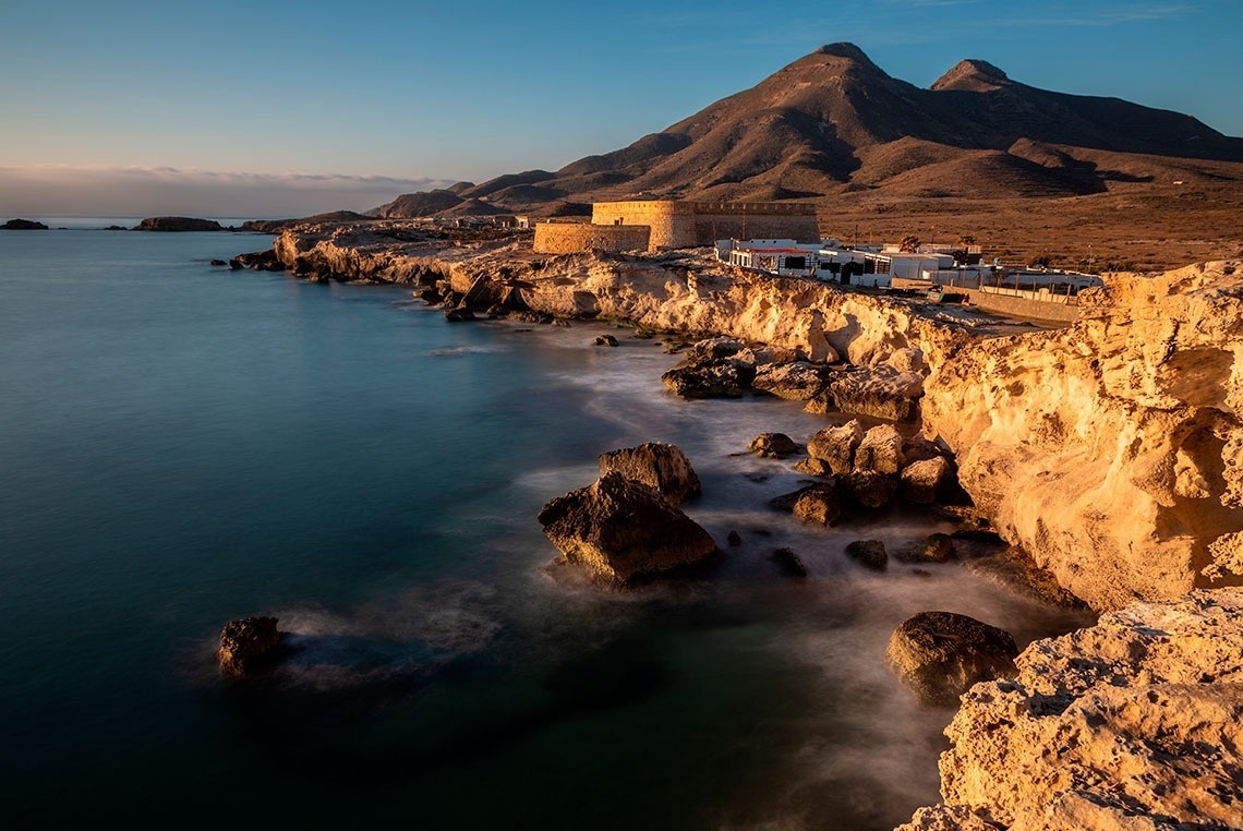 una playa con rocas y montañas en el fondo