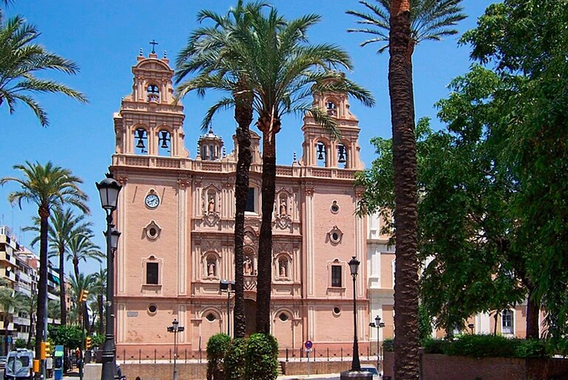 une grande église avec des palmiers devant elle