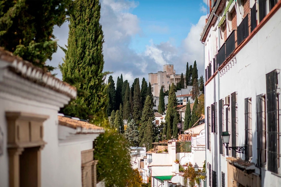 uma rua com muitos prédios brancos e árvores ao fundo