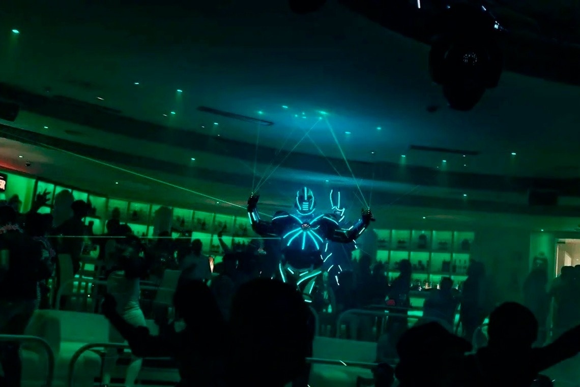 un grupo de personas bailan en una habitación oscura con luces verdes