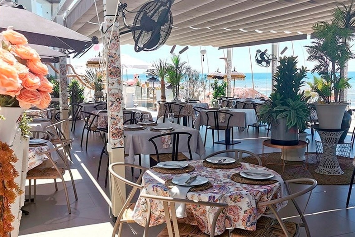 un restaurante lleno de mesas y sillas con una vista al océano