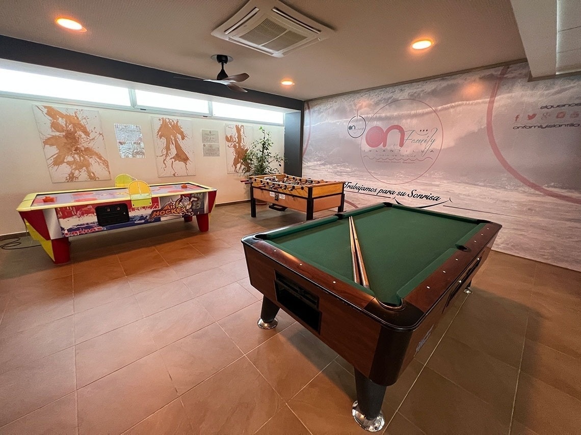 a pool table in a room with a wall behind it that says " trabajamos para su sonrisa "