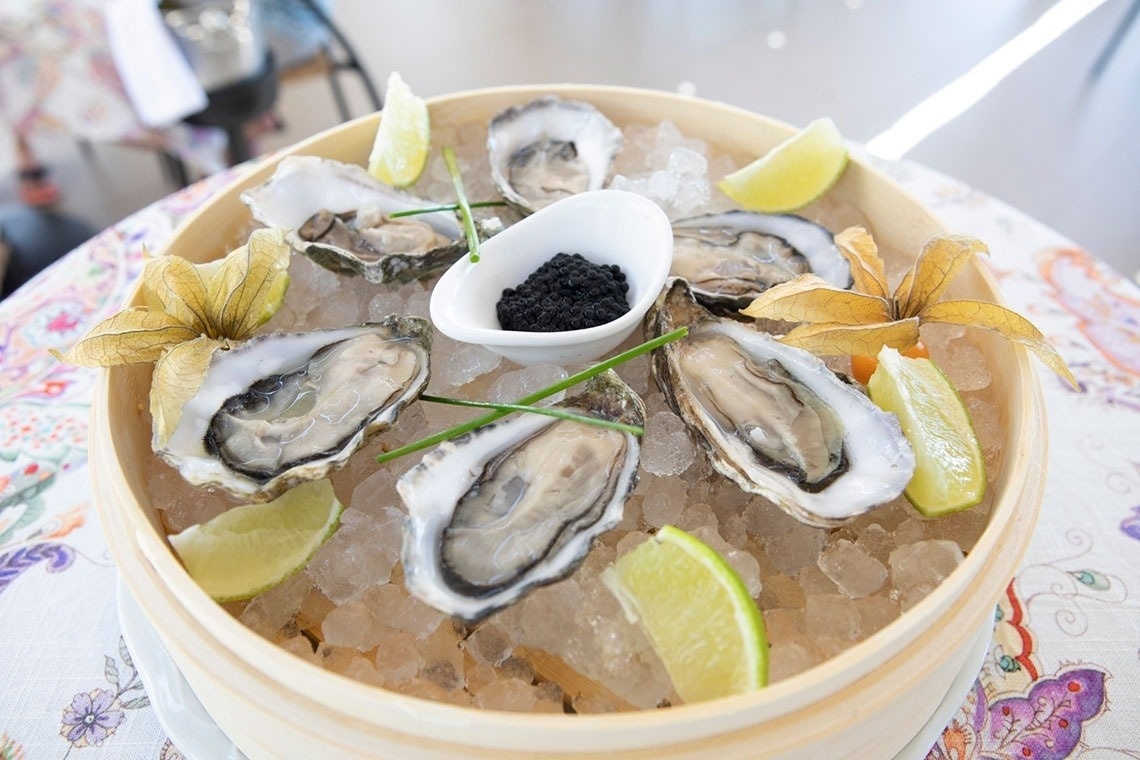 a bowl of oysters on ice with limes and caviar