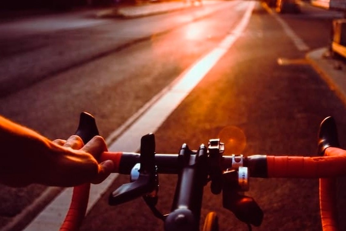 uma pessoa está andando de bicicleta na estrada ao pôr do sol