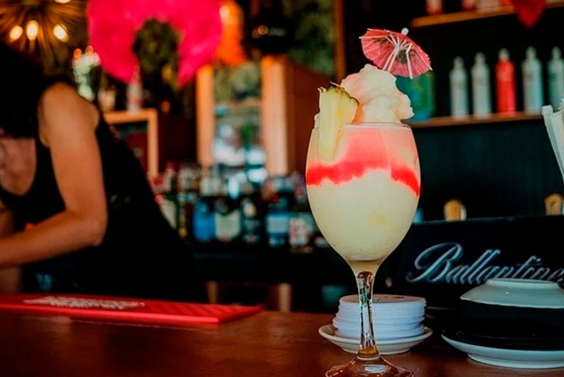 a drink in a ballantine glass with an umbrella on top