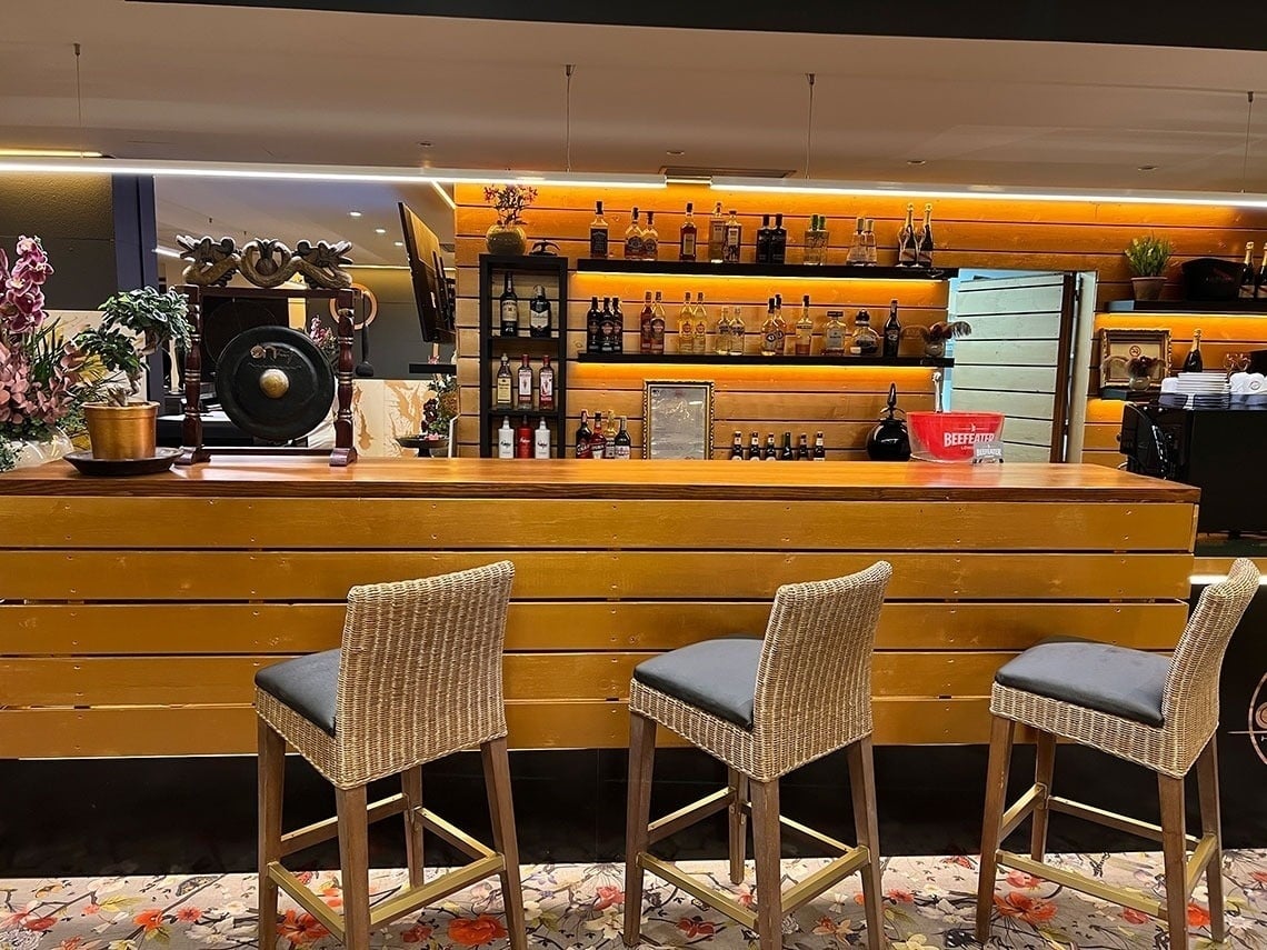un bar con sillas de mimbre y botellas de alcohol en los estantes