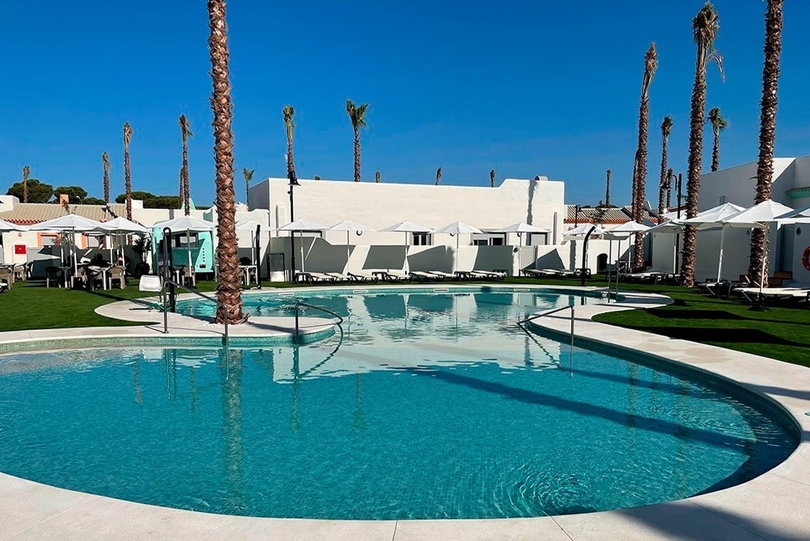 a large swimming pool surrounded by palm trees and umbrellas