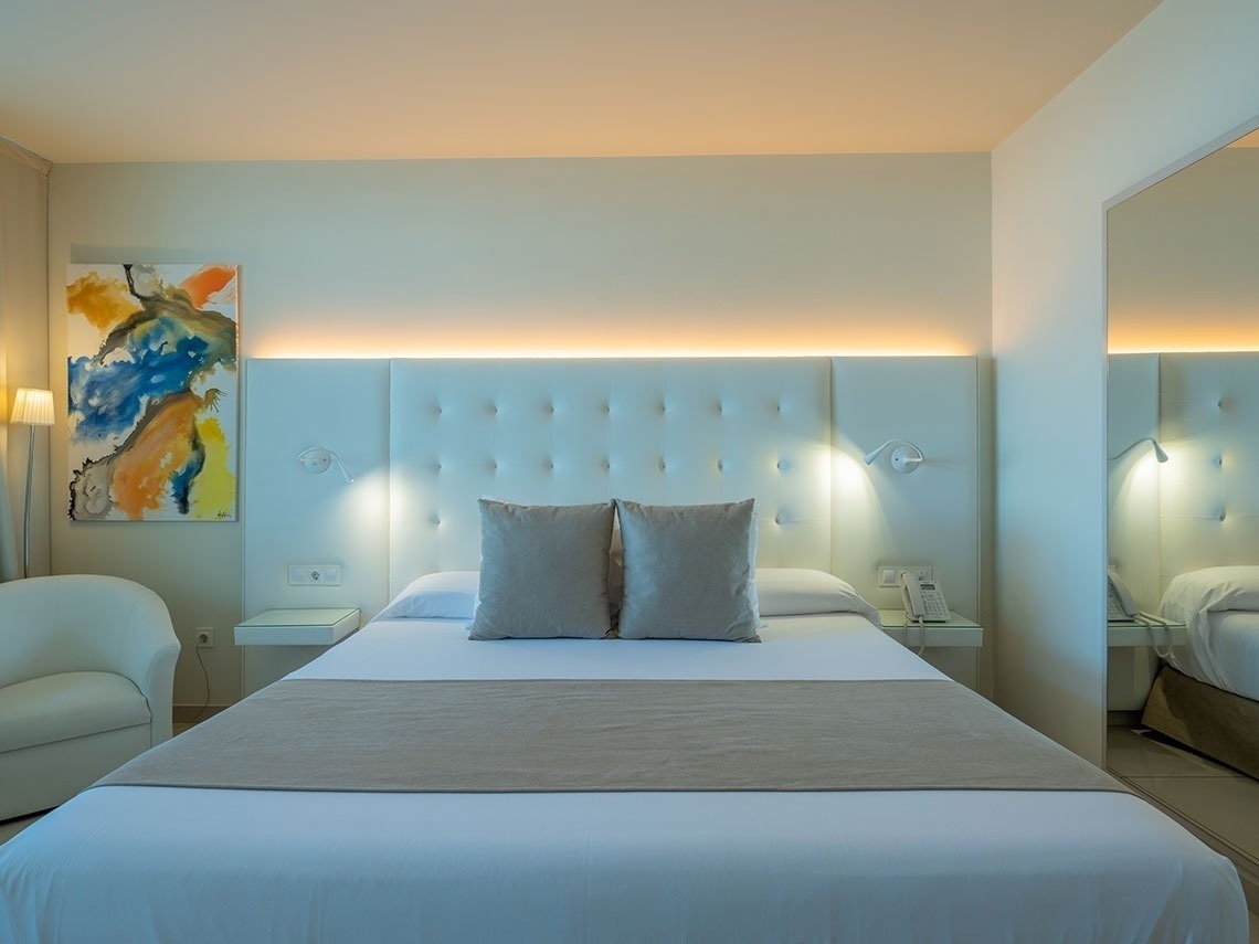 una cama blanca con dos almohadas y una pintura en la pared