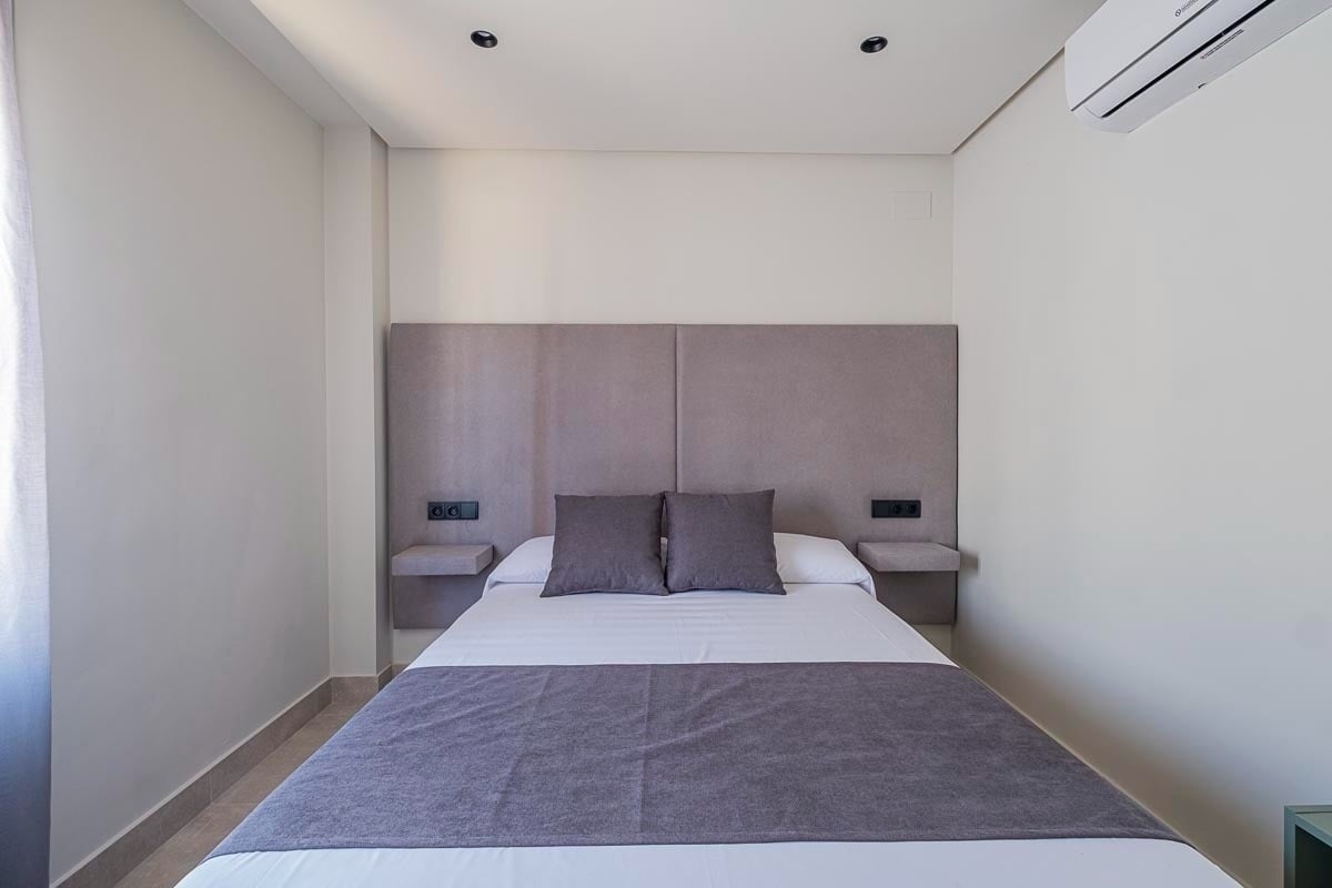 una pequeña habitación con una cama y un aire acondicionado