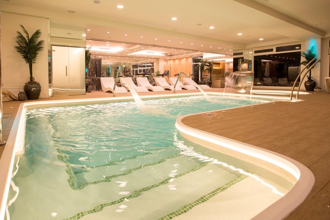 a large indoor swimming pool with chairs and a waterfall