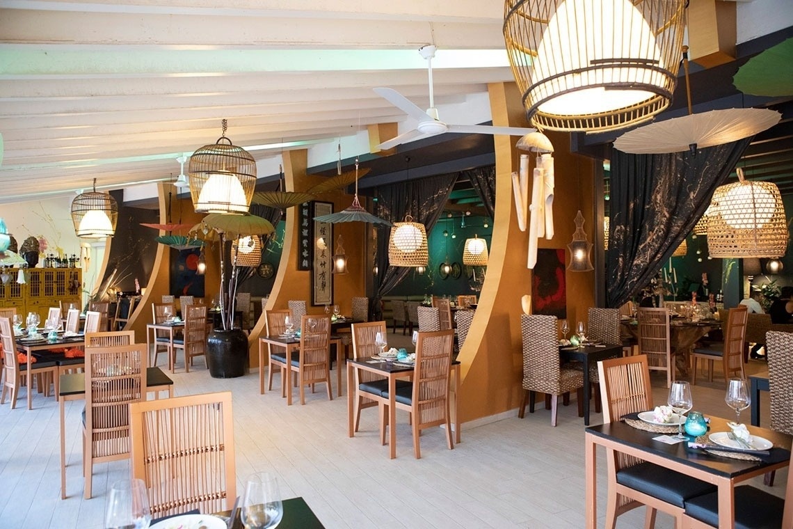 un restaurante lleno de mesas y sillas con paraguas colgando del techo
