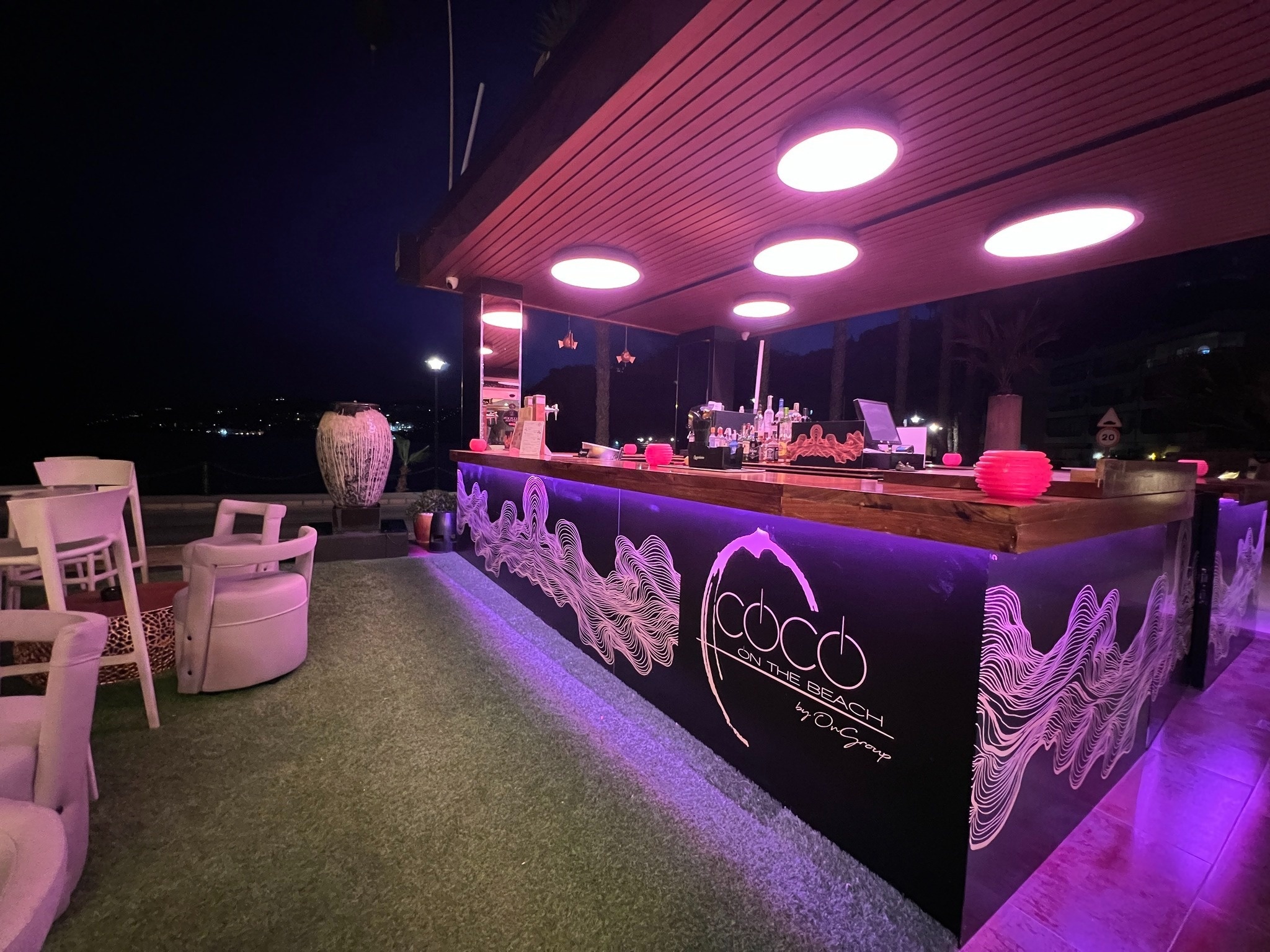 un bar avec des lumières violettes et le logo coco