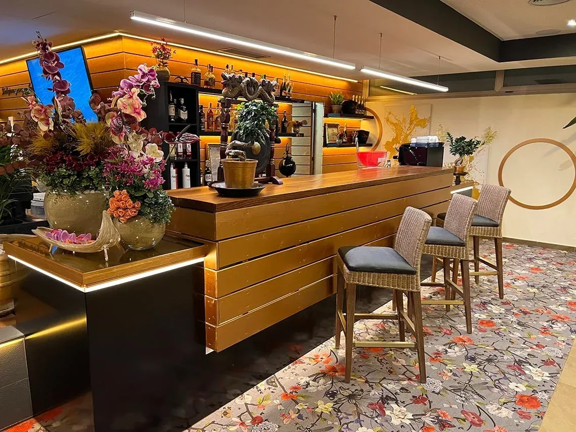 Bar moderno con sillas estilo mimbre y alfombra floral en ON Family Islantilla. Web oficial Huelva.
