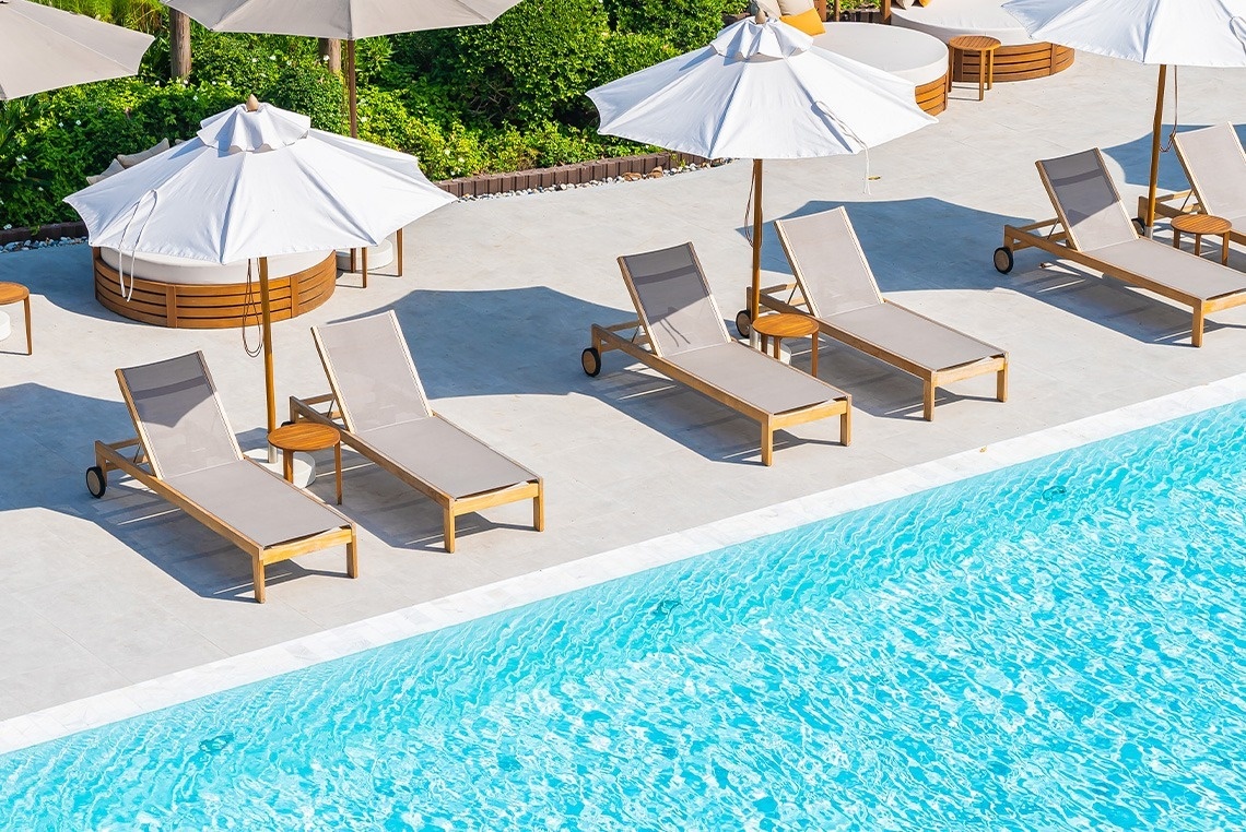a row of lounge chairs and umbrellas next to a swimming pool