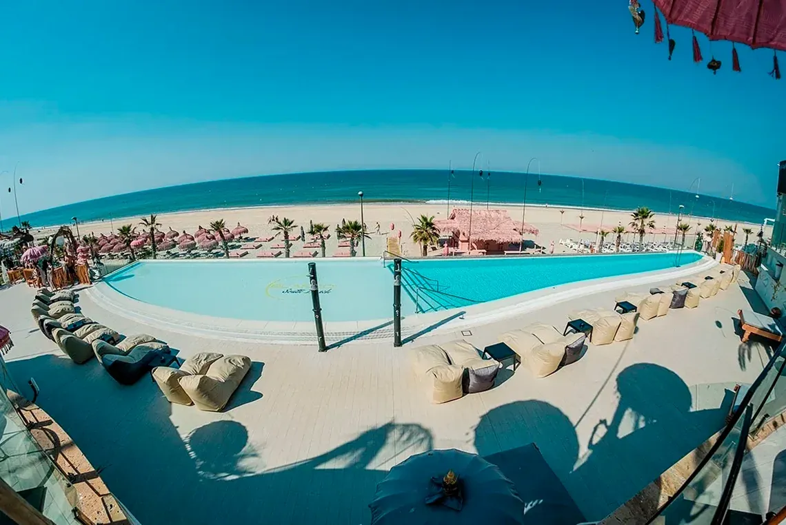 Piscina frente a la playa con tumbonas y cabañas, ideal para On Hotels.