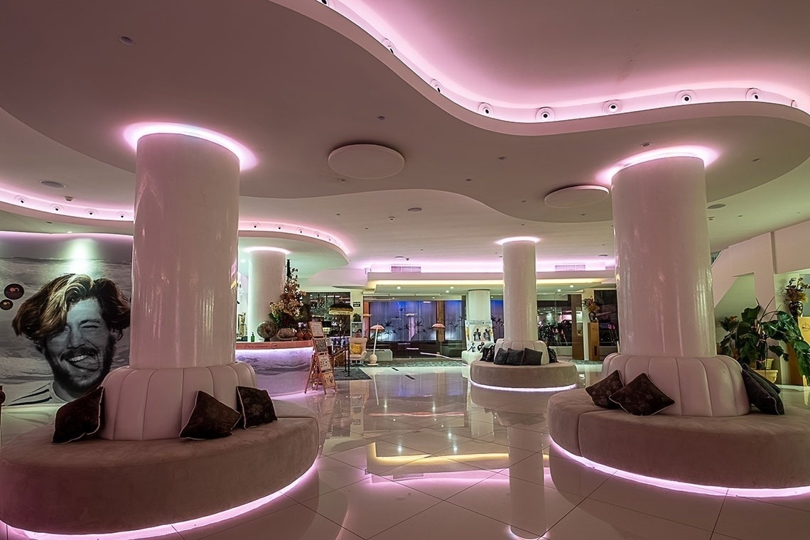 un lobby de un hotel con sofás y columnas y luces rosadas