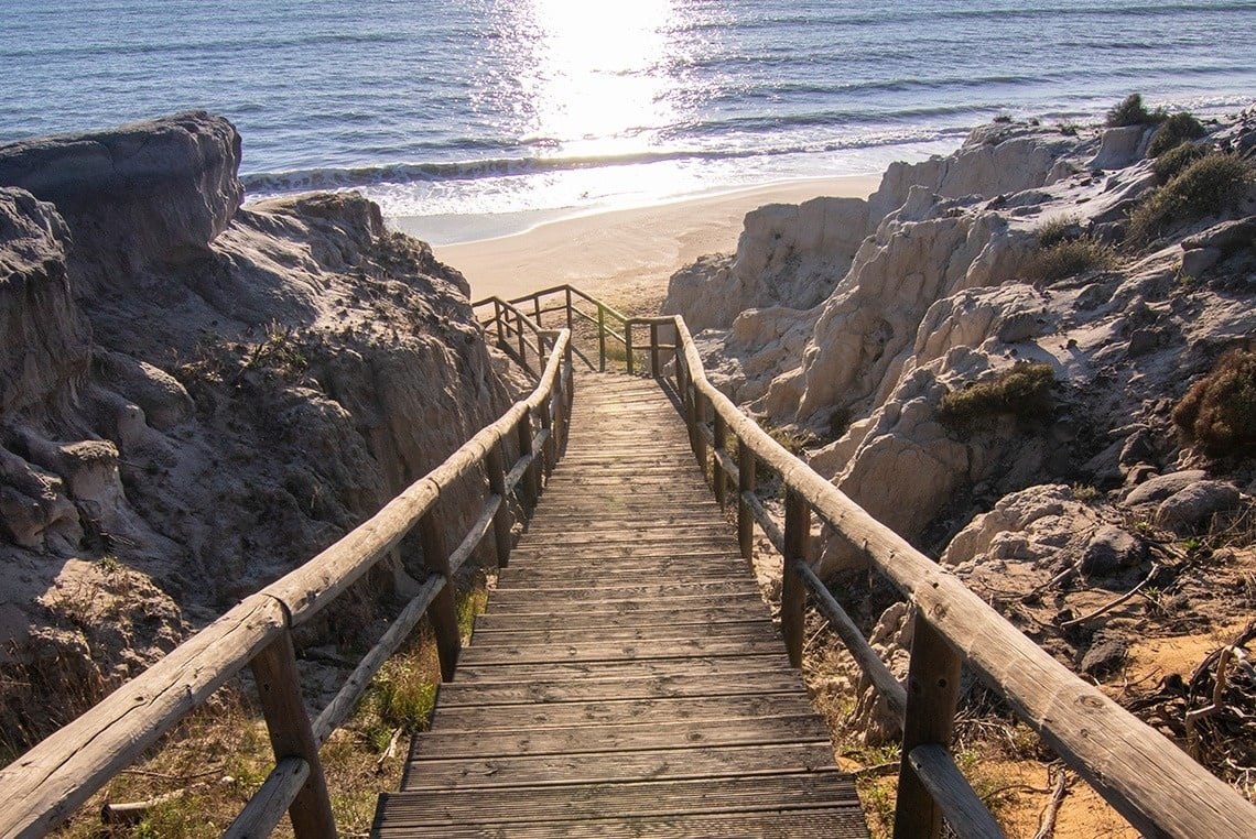 eine Holztreppe führt hinunter zu einem Strand