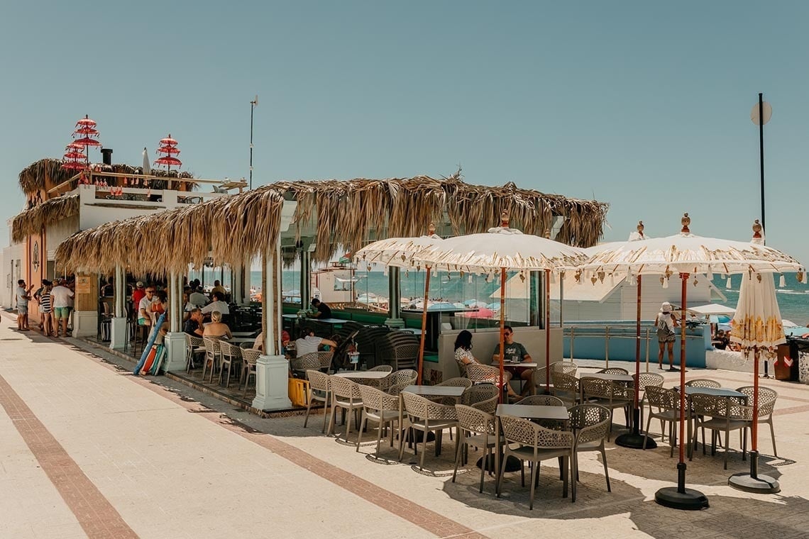un restaurante en la playa con mesas y sombrillas