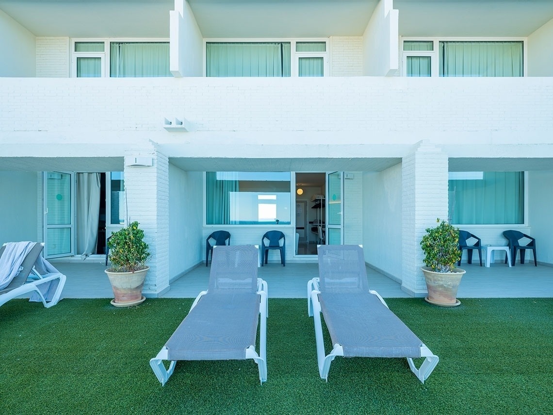 two lounge chairs sit on a lawn in front of a white building