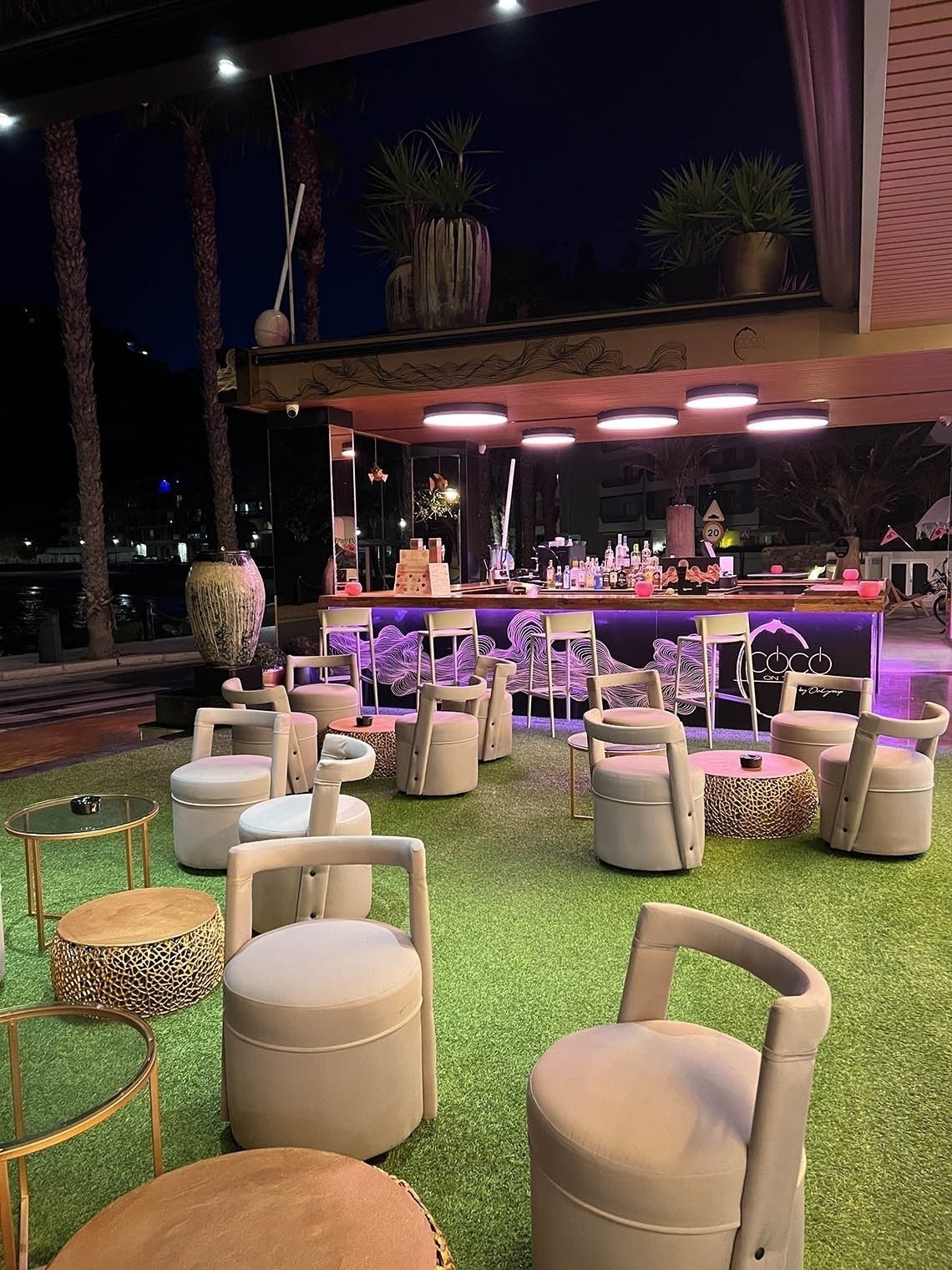un bar con sillas y mesas al aire libre por la noche