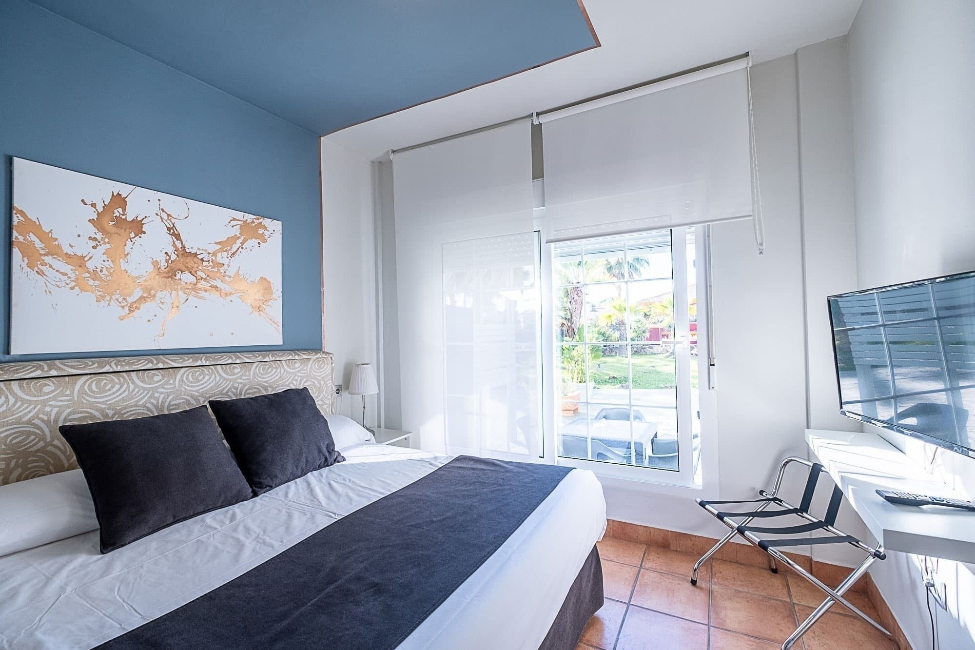 a bedroom with a painting on the wall above the bed