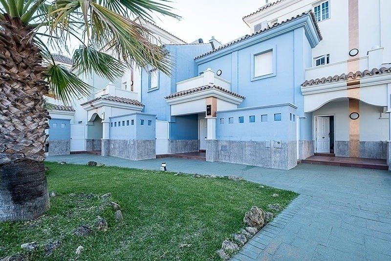 una casa azul y blanca con una palmera al frente